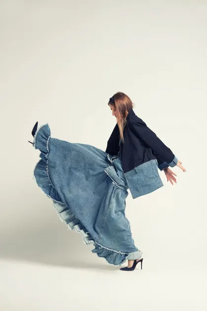Fırfırlı denim etekli kadın model, dans eder gibi bir pozda
