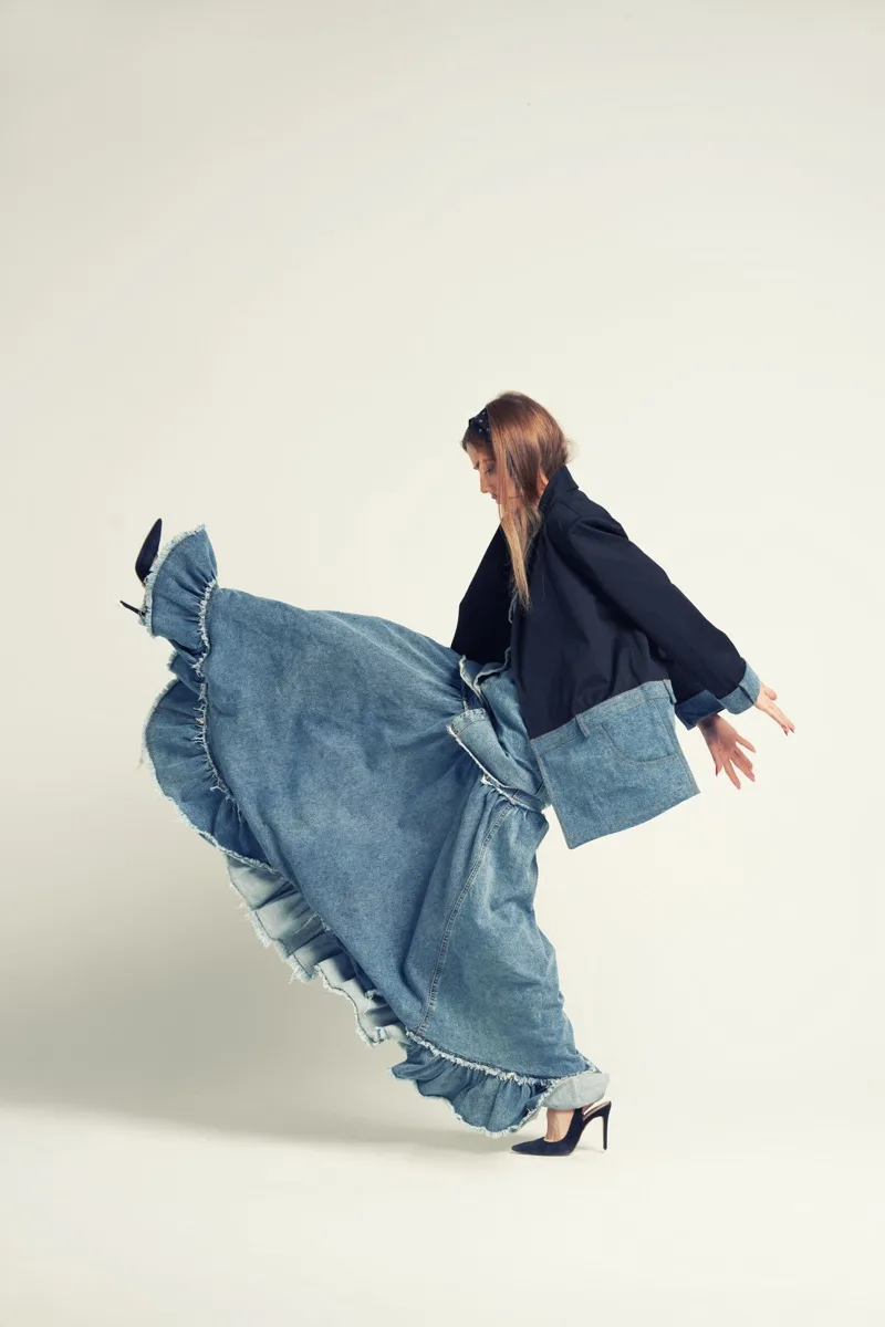 Fırfırlı denim etekli kadın model, dans eder gibi bir pozda